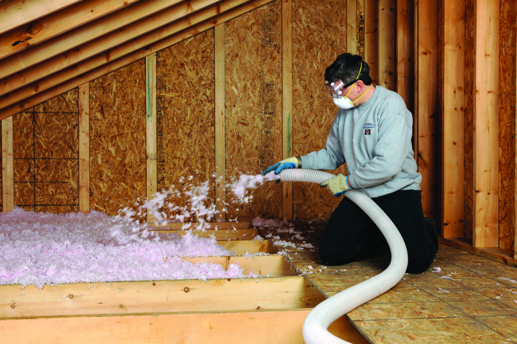 worker installing blown in attic insulation